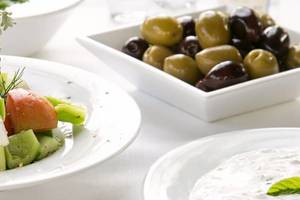 Ein Tisch des Nissi Beach Resorts mit einem gemischten Salat, Oliven und Tzatziki