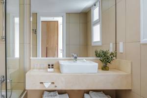 Badezimmer im Nissi Beach Resort mit einer Dusche, einem Waschbecken und einem Spiegel.