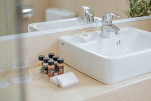 Badezimmer im Nissi Beach Resort mit einem weißen Waschbecken, Handtüchern und Toilette im Hintergrund.