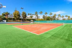 Tennisplatz im Nissi Beach Resort mit grünem Kunstrasen und roten Spielfeldern.