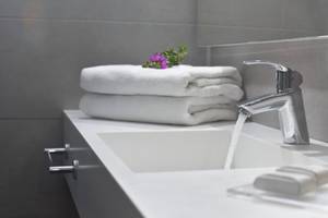 Badezimmer im Nissi Beach Resort mit fließendem Wasser, Handtüchern und Pflegeprodukten.
