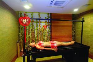 Eine Frau liegt auf einer schwarzen Massageliege im Spa-Bereich des Royal Dragon Hotels.