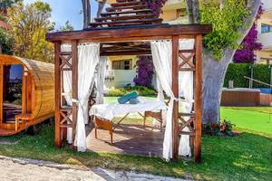 Außenbereich des Viva Golf Adults Only Hotels mit einer Holzsauna und einem Massagetisch unter einer Pergola.