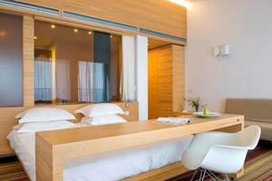 Ein modernes Hotelzimmer im Doryssa Seaside Resort mit einem Bett, Schreibtisch und Couch.