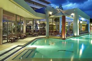 Außenbereich des Dionysos Hotels bei Nacht mit Pool und beleuchteten Tischen und Stühlen.