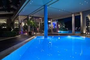 Außenbereich des Dionysos Hotels bei Nacht mit beleuchtetem Pool und moderner Architektur.