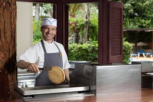 Koch im Dionysos Hotel bereitet Waffeln auf einem Grill zu.