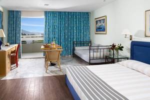 Innenansicht eines Zimmers im Dionysos Hotel mit Bett, Schlafsofa und Balkon.