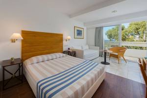Innenansicht eines Hotelzimmers im Dionysos Hotel mit Bett, Couch, Tisch und Balkon