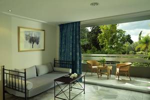 Der Balkon des Dionysos Hotels mit einer Couch, einem Tisch und zwei Stühlen, Blick auf die Natur