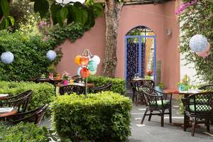 Gartenterrasse des Dionysos Hotels mit bunten Dekorationen und begrünten Bereichen.