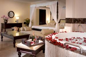 Luxuriöse Suite im TRS Turquesa Hotel mit Badewanne, Bett und Rosenblättern.
