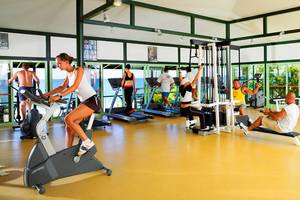 Fitnessstudio im Hotel Marti Myra mit mehreren Personen, die auf verschiedenen Geräten trainieren.