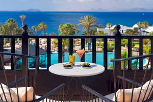 Terrasse des H10 Rubicon Palace mit Blick auf das Meer und Cocktails auf dem Tisch.