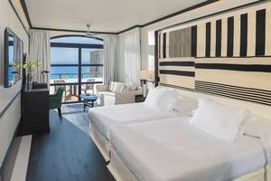 Doppelzimmer mit Meerblick im H10 Rubicon Palace Hotel mit zwei Betten, einem Schreibtisch und einem Sofa.