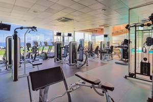 Fitnesscenter im H10 Rubicon Palace Hotel mit modernen Trainingsgeräten und einem Ausblick auf das Schwimmbad.