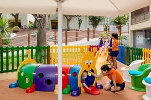 Kinderspielplatz im Freien im H10 Rubicon Palace Hotel mit bunten Spielgeräten und einer Frau, die ein Kind beobachtet.