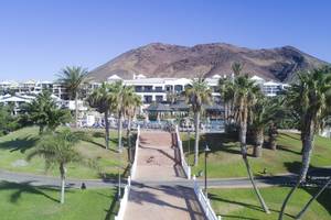 Luftaufnahme des H10 Rubicon Palace mit Palmen und einer Treppe zum Eingang vor einem Berg