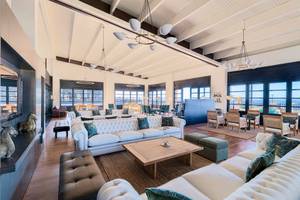 Lobby des H10 Rubicon Palace mit weißen Sofas, Holztischen und Panoramafenstern.