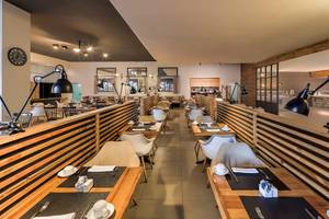 Innenansicht des Restaurants im H10 Rubicon Palace Hotel mit modernen Holztischen und Stühlen.