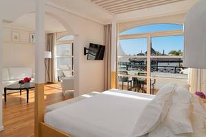 Innenansicht eines Hotelzimmers im H10 Rubicon Palace mit Bett, Sofa, Tisch, Fernseher und Balkon