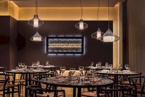 Innenansicht des Restaurants im H10 Rubicon Palace Hotel mit runden Tischen, Stühlen und dekorativen Lampen.