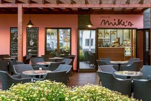 Innenbereich des Mike's Cafe im H10 Rubicon Palace Hotel mit Tischen und Stühlen.