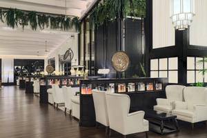 Innenansicht des H10 Rubicon Palace Hotels, Loungebereich mit weißen Sesseln, B ücherwand und schwarzem Tisch.