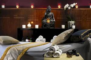 Wellnessbereich im H10 Rubicon Palace Hotel mit einem Bett, Kissen, Buddha-Statue und Kerzen