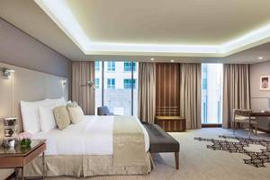 Hotelzimmer im Grand Millennium Muscat mit großem Bett, Schreibtisch und Fenstern.
