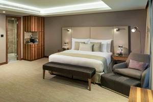 Innenansicht einer Hotelsuite im Grand Millennium Muscat mit großem Bett, Sitzbereich und moderner Einrichtung.