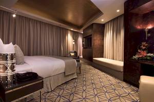Schlafzimmer im Grand Millennium Muscat Hotel mit Bett, Sitzecke und Dekor