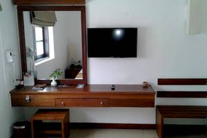 Ein Zimmer mit einem Spiegel, Fernseher und Schreibtisch im Goldi Sands Hotel.