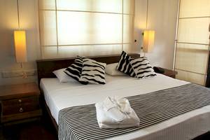 Doppelbett im Schlafzimmer des Goldi Sands Hotels mit weißen Laken und schwarzen und weißen Kissen.