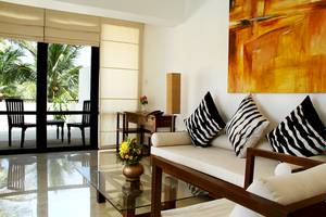 Wohnzimmer im Goldi Sands Hotel mit einem Sofa, Kissen, Tisch und Blick auf Palmen