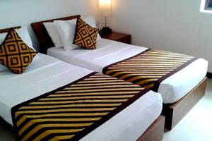 Zwei Betten im Goldi Sands Hotel mit farbigen Kissen und gestreiften Decken.
