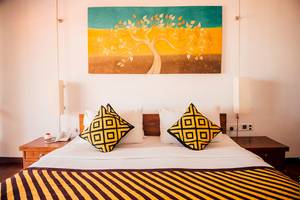 Goldi Sands Hotel Schlafzimmer mit Bett, Kissen und Wandmalerei.