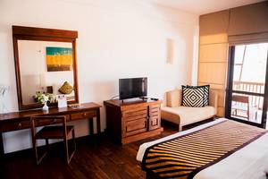 Ein elegantes Hotelzimmer von Goldi Sands mit einem großen Bett, einem Schreibtisch und einem Fernseher.