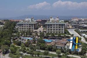 Luftaufnahme des Adalya Bliss Hotels mit Pools, Wasserrutschen und umgebenden Bäumen.