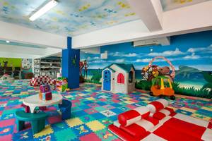 Kinderspielzimmer im Occidental Caribe Hotel mit bunten Bodenfliesen, Spielzeug und Wandmalerei.