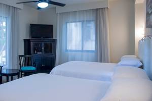 Hotelzimmer im Allegro Playacar mit zwei Betten, einem Fernseher und Möbeln.