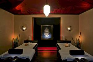 Massageraum im Elite Suites by Rhodes Bay mit zwei Massagetischen, Buddha-Bild und roten Akzentbeleuchtung.