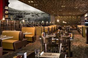 Innenbereich des Speiserestaurants im Mirage Hotel & Casino mit gelben Ledersitzen und einer großen Wandmalerei.
