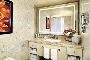 Das Badezimmer im Mirage Hotel & Casino mit einer großen Spiegelwand, einem Waschbecken und einer Toilette.