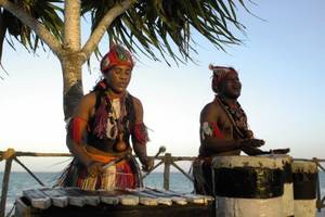 Zwei Männer spielen traditionelle Musikinstrumente am Strand des Ocean Paradise Resort & Spa.