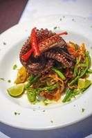 Ein Teller mit gegrilltem Oktopus, serviert auf einem weißen Teller.