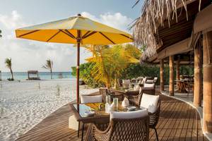 Strandrestaurant im Drift Thelu Veliga Retreat mit gelbem Sonnenschirm und Tisch vor dem Meer