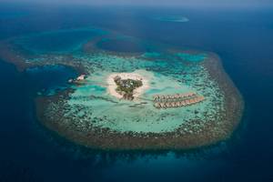 Luftaufnahme des Drift Thelu Veliga Retreat, einer Insel mit vielen Bungalows und einem Steg.