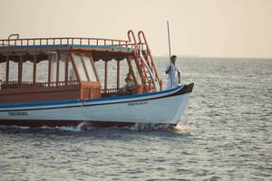 Ein Boot mit Passagieren und Kapitän im Meer während des Sonnenuntergangs
