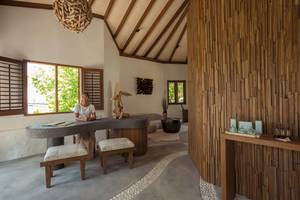 Innenansicht des Drift Thelu Veliga Retreat mit einer Frau am Schreibtisch und Holzwänden.